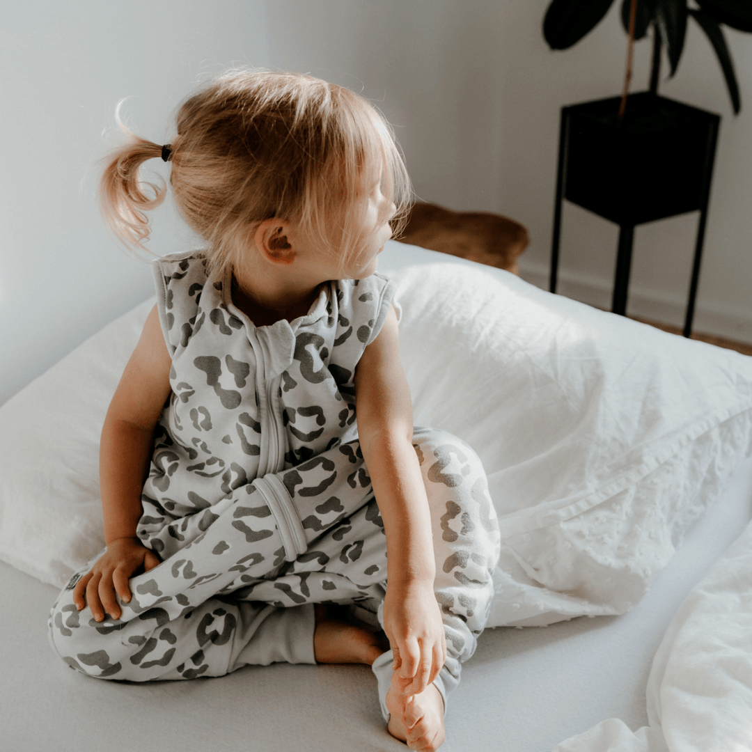 Kleines Mädchen im Schlafsack mit Füßen Leo grau